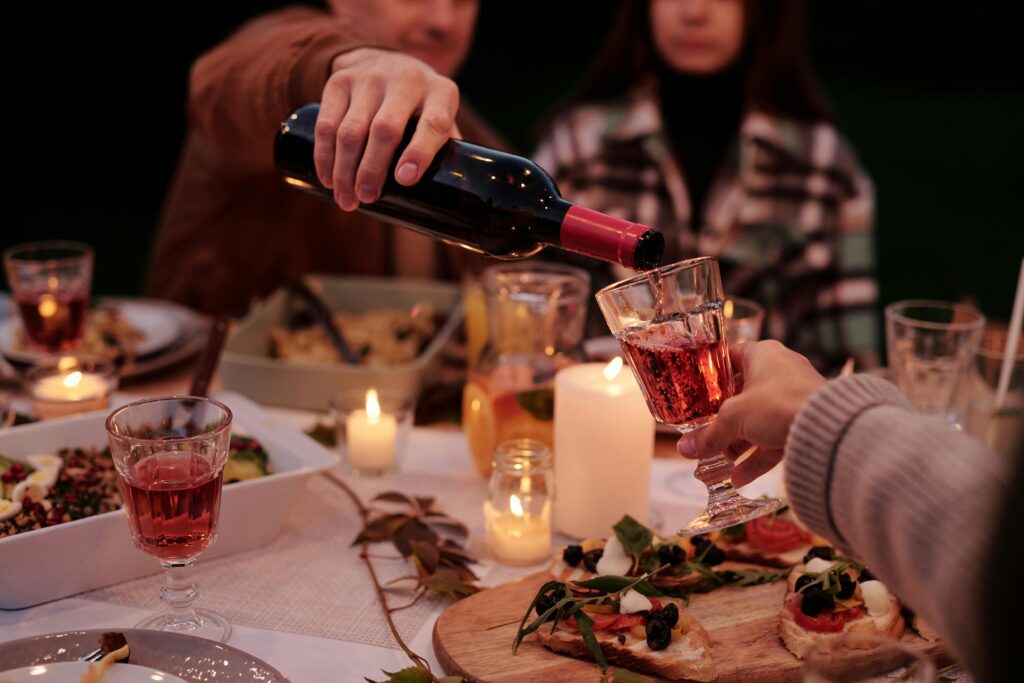 Crop man pouring wine to people on family dinner